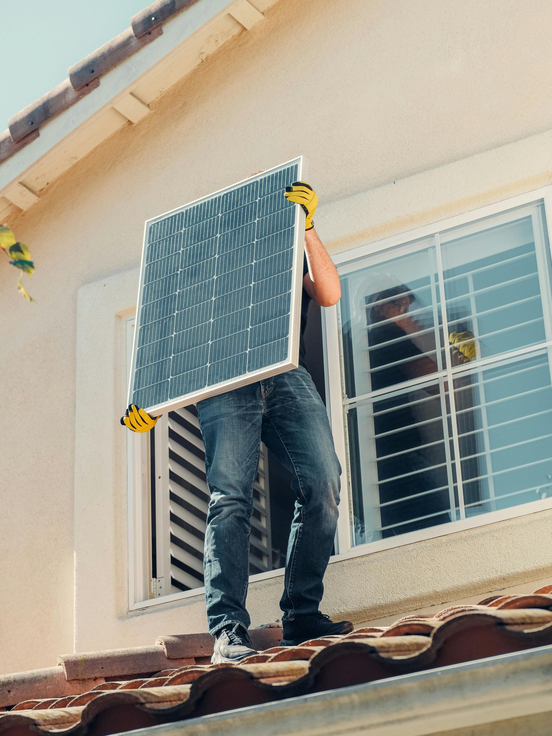 Person installing solar panel on a roof