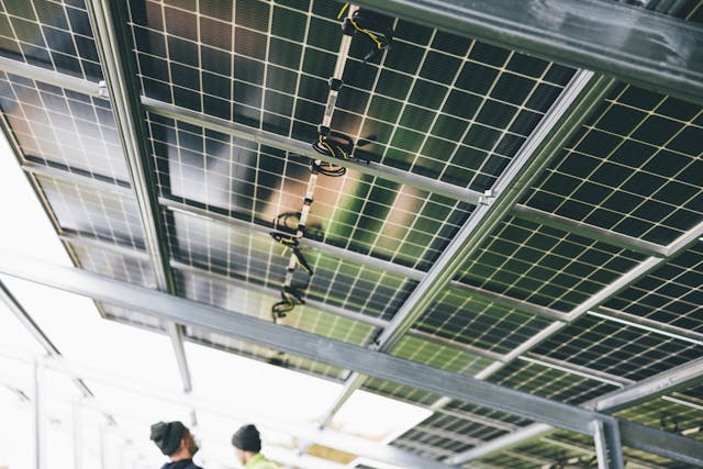 two men standing below the tilted solar panels.