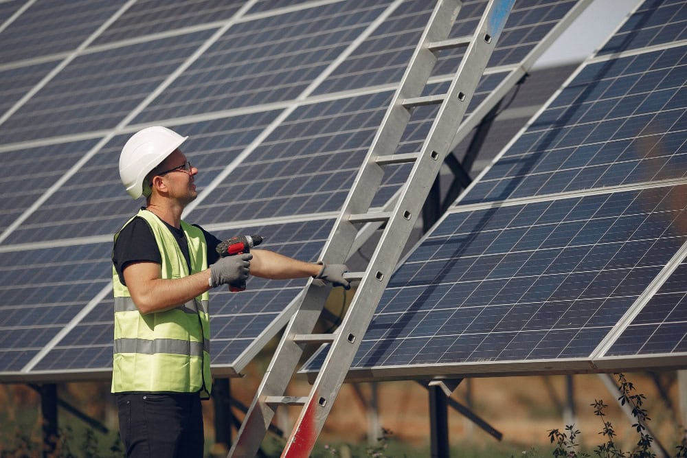 Solar panel installation in progress. The panels are being mounted on a rooftop with a clear blue sky in the background.