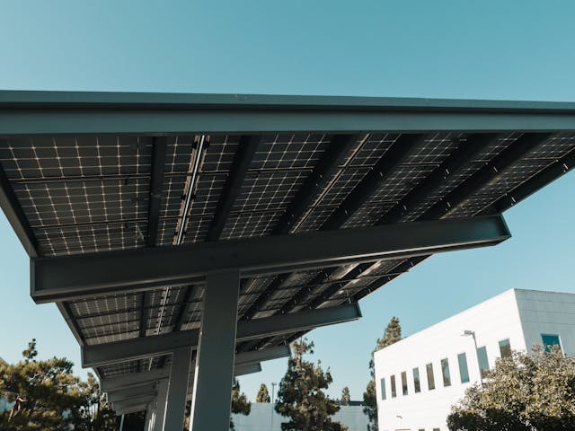 A close-up of solar panels installed on a metal structure, with a clear blue sky in the background. 