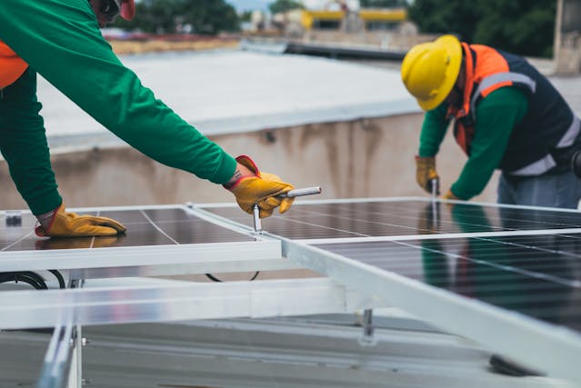 Two men mounting solar panels on a rooftop