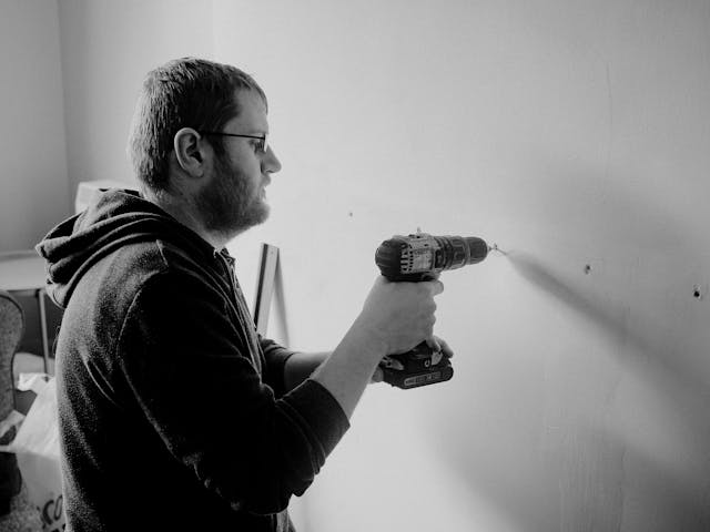 Man drilling a hole in the wall.