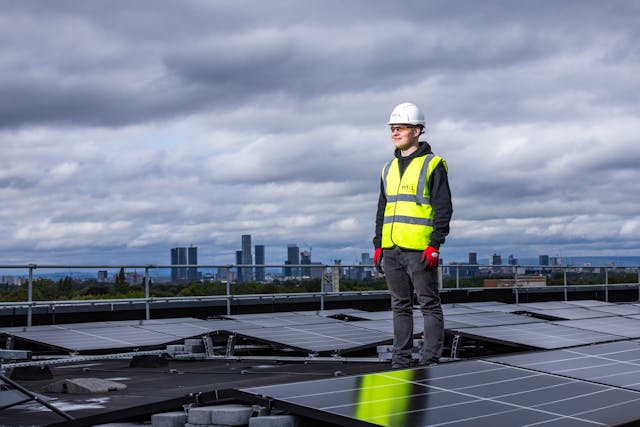 A man working on solar panels on rooftop of a building.