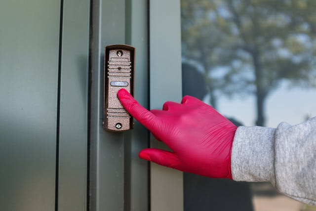 A hand pressing the intercom button.